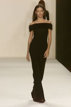 a woman walking down a runway in a black dress