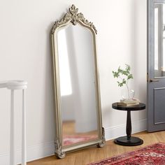 a large mirror sitting on top of a wooden floor next to a table and chair