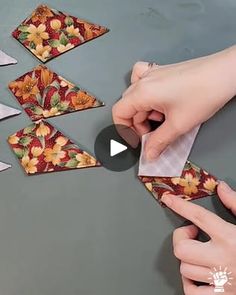 someone is cutting paper with scissors on top of a table that has flowers and leaves