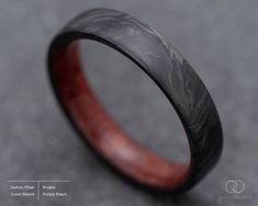 a wooden ring with black and red inlays on the inside, sitting on a gray surface