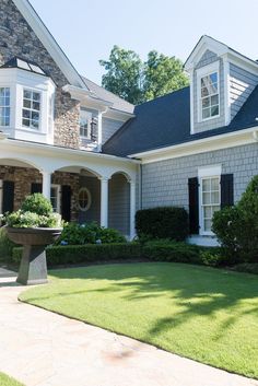 a large gray house with white trim and black shutters on the windows, grass in front