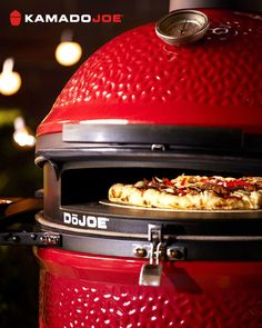 a close up of a pizza on top of a red bbq with lights in the background