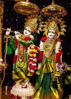 two deities dressed in green and yellow with flowers on their heads, standing next to each other