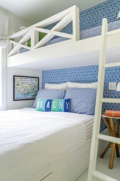 a white bunk bed sitting next to a blue and white wall with a ladder on it