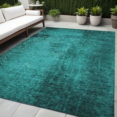 a green rug on the ground in front of a white couch and potted plants