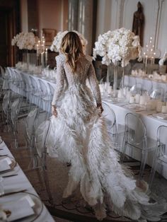 the back of a woman's dress at a table with white flowers and candles