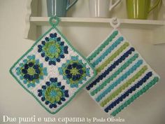 two crocheted dishcloths hanging on a shelf next to cups and mugs