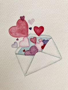 an envelope with hearts coming out of it on top of a piece of white paper