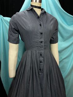 "1950s W:26 Vintage 50s Charcoal Grey Poly Cotton Shirtdress Button Up Short Sleeve Peter Pan Collar Flower Crochet Button Fit Flare skirt  Vintage 50s beautiful fit and flare classic pullover style shirt dress. Charcoal grey colored with chambray like texture on poly cotton fabric. Button up with placket and double buttons, functional and sewn on crochet black flowers. Little Peter Pan collar and short cuffed sleeve. Skirt pleated fit and flare. Photographed on fit form size 2, please check measurements, added red petticoat not included. MEASUREMENTS  Bust: 39\" Waist: 26\" Hips: free Bodice length: 16 1/2\" Skirt length: 25\"  Length: 42\" with 4\" hem available to let down Sleeve: 12\" (not cuffed) This is in good vintage condition, presents beautifully and is completely wearable as is! Classic A-line Vintage Dress With Buttons, Classic A-line Vintage Dress With Button Closure, 1950s Style Knee-length Dress With Button Closure, Classic Tea-length Vintage Dress, Vintage Cotton Dress With Buttons, Vintage Dress With Button Closure For Vintage Fashion, Retro Vintage Dress With Button Closure, Fitted Vintage Dress With Buttons For Daywear, Cotton Vintage Dress With Buttons