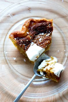 a piece of cake on a glass plate with a spoon in it and whipped cream