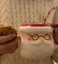 a person holding a cookie in front of a santa clause mug