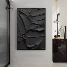 a black and white painting hanging on the wall next to a cabinet in a room