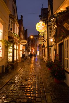 a cobblestone street at night with people walking down it