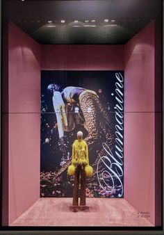 a mannequin is standing in front of a pink wall with an advertisement on it