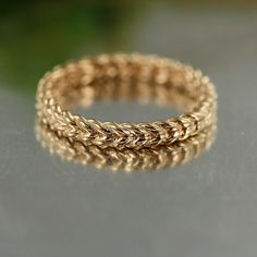 a gold braided ring sitting on top of a gray table next to a green plant