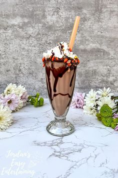 a chocolate milkshake with marshmallows and candy on the rim, garnished with flowers