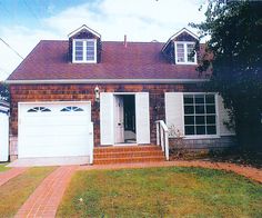 a brick house with two garages and a white door on the front porch is shown