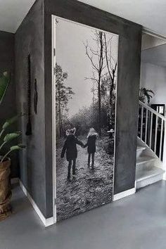 two children are holding hands in front of a black and white photo on the wall