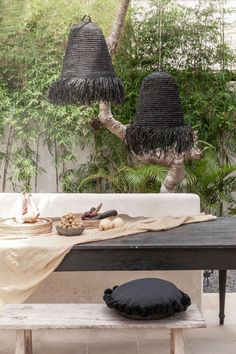 two black lamps hanging from the ceiling above a table with food on it and pillows