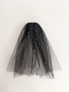 a black tulle skirt hanging on the wall with white stars and pearls in it