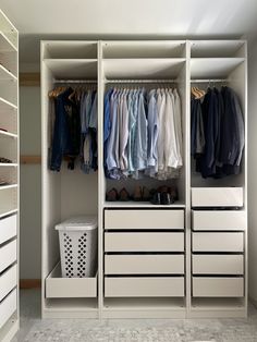 an organized closet with white drawers and clothes hanging on the rails, along with a laundry basket