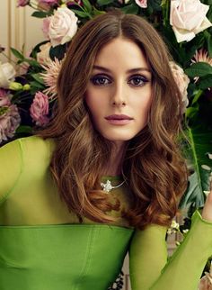 a woman in a green dress with flowers behind her