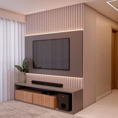 the television is mounted on the wall in the living room, and it's illuminated by lights