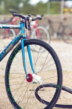 a blue bicycle parked on top of a dirt road next to bicycles in the background