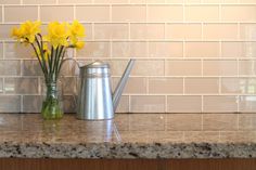 yellow daffodils are in a vase on the kitchen counter next to a watering can