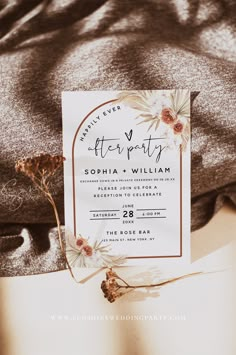 a wedding card laying on top of a bed next to a flowery pillow and blanket