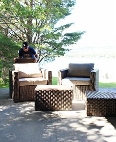 a man sitting on top of an outdoor chair next to a tree and some chairs