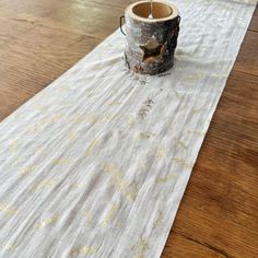 a white table runner with gold stars on it and a wooden mug sitting on top