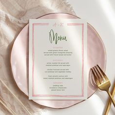 a pink plate with a menu on it next to gold utensils and a fork