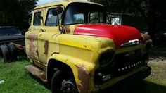 an old yellow and red truck parked in the grass