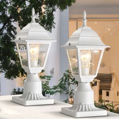 two white street lamps sitting on top of a table