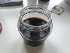 a glass jar filled with liquid sitting on top of a white table next to other items