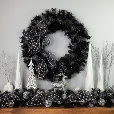 a christmas wreath and other decorations on a mantel with white trees in the background