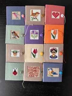 several cross stitch cards are arranged on a table with pins and thread in them,