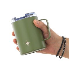 a hand holding a green coffee mug with a star on the side and a chain around it