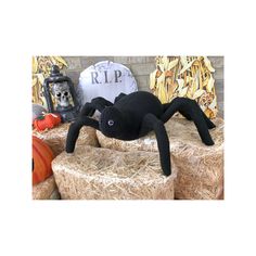 a stuffed spider sitting on top of hay next to pumpkins and other halloween decorations