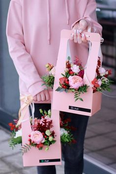 a person holding two pink bags with flowers on them