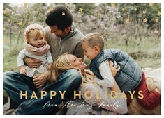 a happy holiday card with an image of two adults and three children sitting on the grass