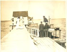 an old photo of people standing on a pier