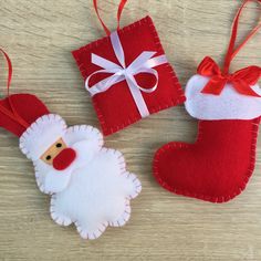 three christmas ornaments are sitting on a wooden table, one is red and the other is white