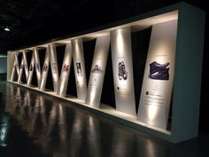 a display case with several different types of shoes on the wall and lights above it