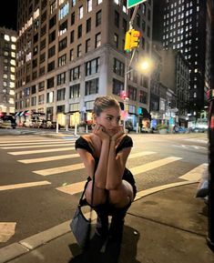 a woman sitting on the side of a street next to a traffic light