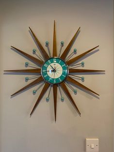 a clock mounted to the side of a wall with wooden sticks sticking out of it