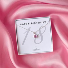 a happy birthday necklace with a pink crystal