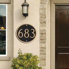 a black and gold address plaque on the side of a building with a lamp above it