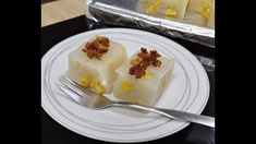 two pieces of cake on a white plate with a fork next to it and tin foil in the background